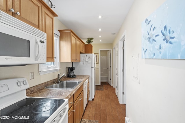 kitchen featuring white appliances, recessed lighting, light wood finished floors, and a sink