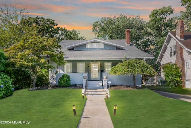 view of front of house featuring covered porch and a lawn