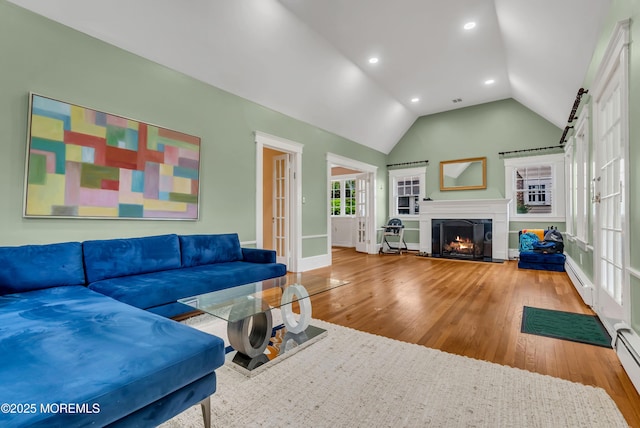 living room featuring a baseboard heating unit, french doors, lofted ceiling, and hardwood / wood-style flooring