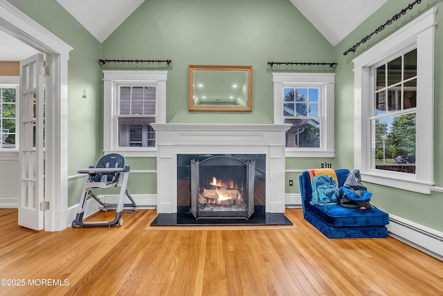 unfurnished room with baseboard heating, wood-type flooring, and lofted ceiling