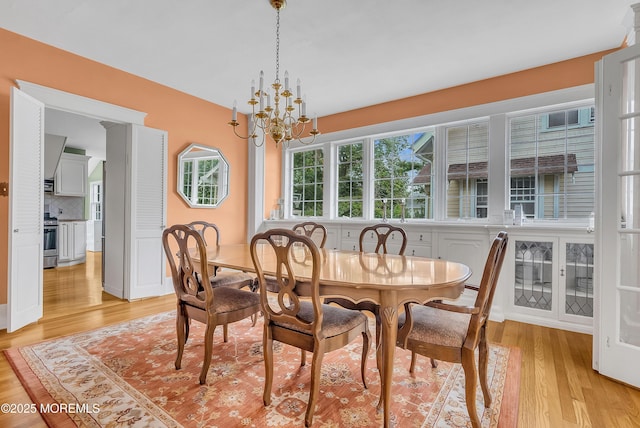 dining area with light wood-type flooring and an inviting chandelier