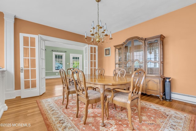 dining area with french doors, a chandelier, a baseboard heating unit, and light wood-type flooring