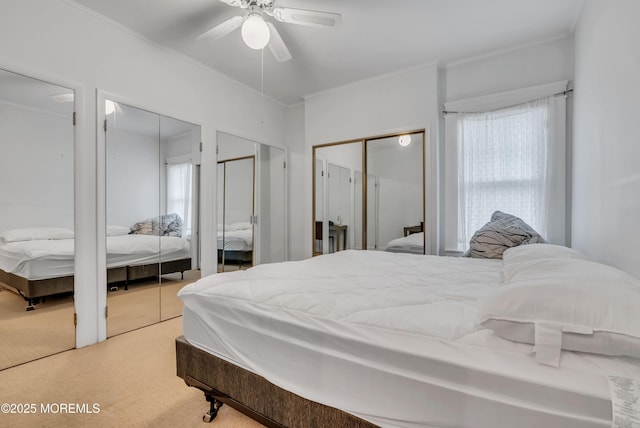 carpeted bedroom featuring ceiling fan, multiple windows, and multiple closets