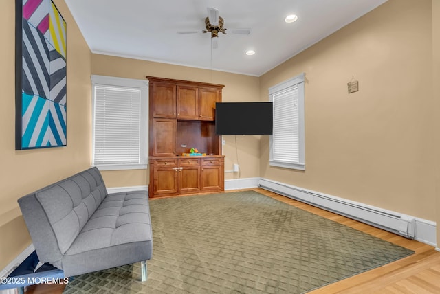 living room with a baseboard radiator, ceiling fan, and light hardwood / wood-style floors