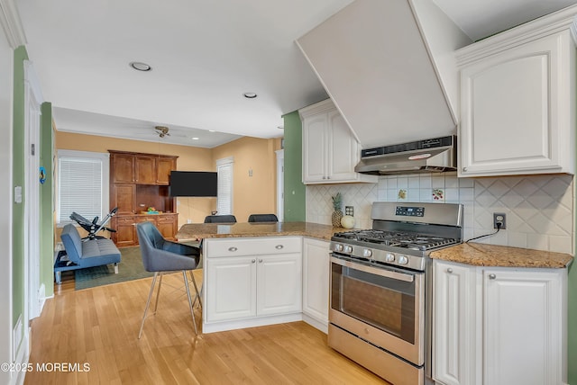 kitchen with kitchen peninsula, stainless steel gas range, exhaust hood, light hardwood / wood-style flooring, and white cabinetry