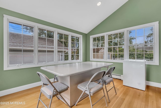 sunroom / solarium featuring a wealth of natural light, a baseboard radiator, and vaulted ceiling