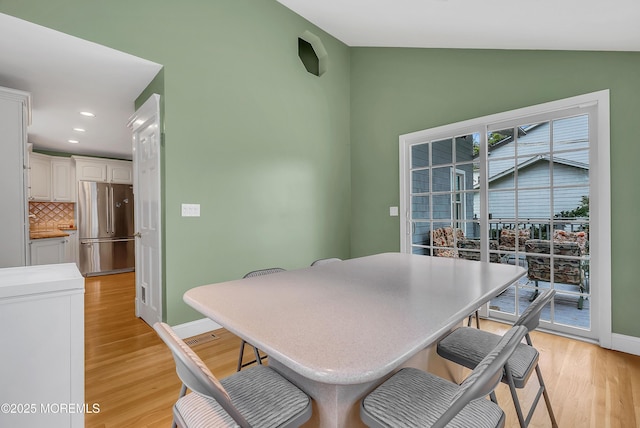 dining space featuring light hardwood / wood-style floors and vaulted ceiling