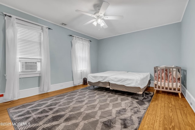 bedroom featuring ceiling fan, crown molding, cooling unit, and wood-type flooring