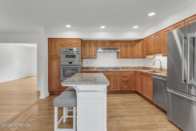 kitchen featuring a center island, stainless steel appliances, a kitchen breakfast bar, and light hardwood / wood-style flooring