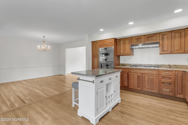 kitchen featuring appliances with stainless steel finishes, a kitchen bar, pendant lighting, and light hardwood / wood-style floors