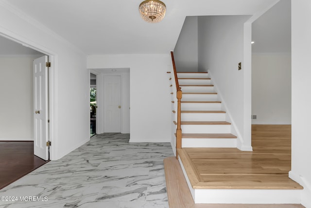 entrance foyer featuring a chandelier and crown molding