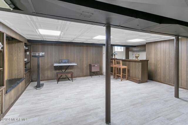 basement with wood walls and light hardwood / wood-style floors