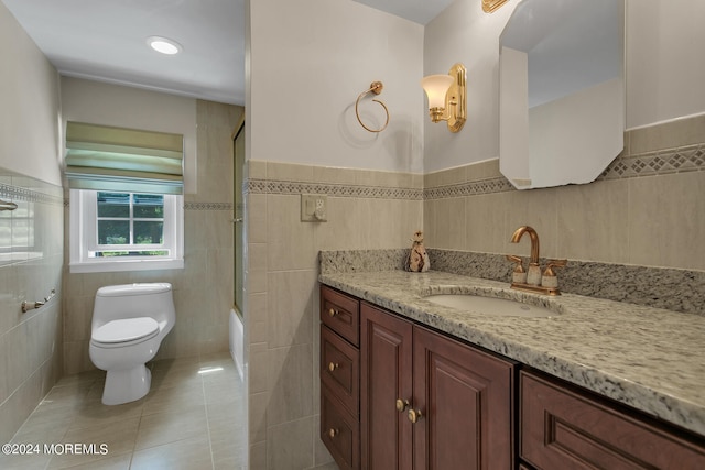 full bathroom featuring toilet, tile patterned floors, vanity, bathing tub / shower combination, and tile walls