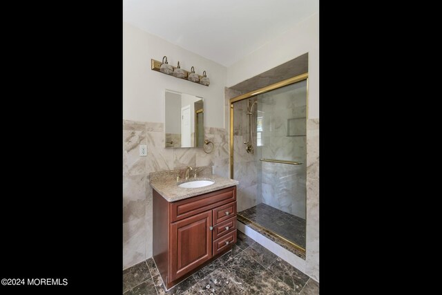 bathroom with vanity, an enclosed shower, and tile walls