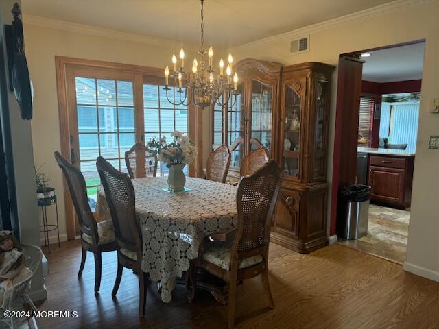 dining room with hardwood / wood-style floors, a chandelier, and ornamental molding