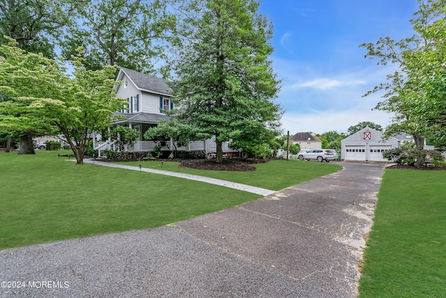 view of front of property with an outbuilding, a front lawn, a shingled roof, and a garage