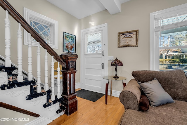 entrance foyer with beam ceiling, baseboards, light wood finished floors, and stairs