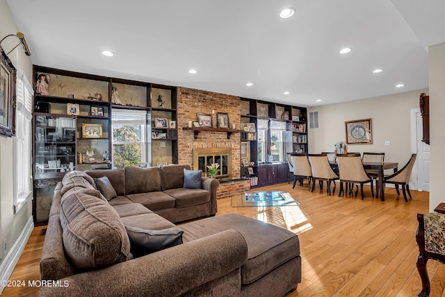 living room featuring light wood finished floors, a brick fireplace, and recessed lighting