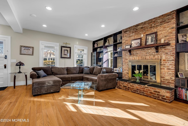 living area with built in shelves, a fireplace, recessed lighting, baseboards, and hardwood / wood-style flooring