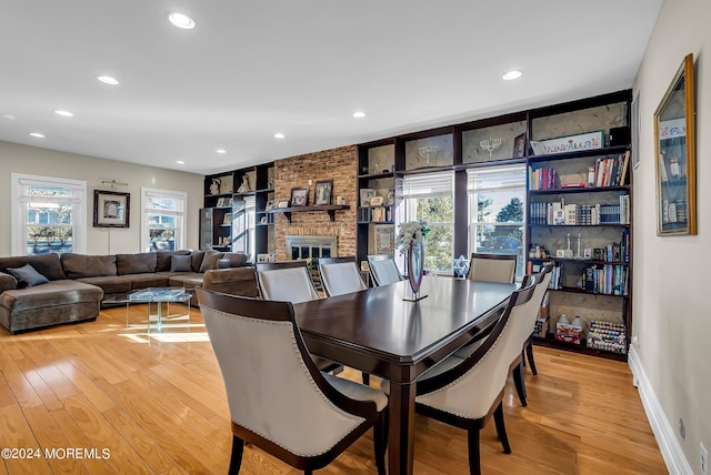 dining room featuring light wood-type flooring, a brick fireplace, and recessed lighting