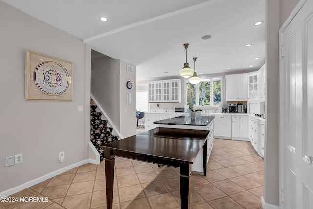 kitchen featuring glass insert cabinets, white cabinetry, decorative light fixtures, and light tile patterned floors