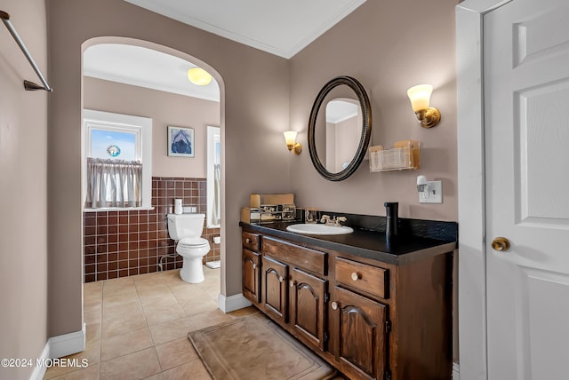 bathroom with crown molding, tile walls, toilet, vanity, and tile patterned floors