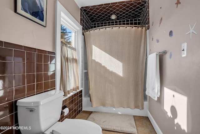 bathroom featuring shower / bathtub combination with curtain, tile patterned flooring, tile walls, and toilet