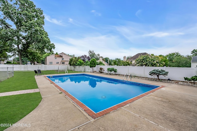 view of swimming pool featuring a fenced in pool, a fenced backyard, a lawn, and a patio