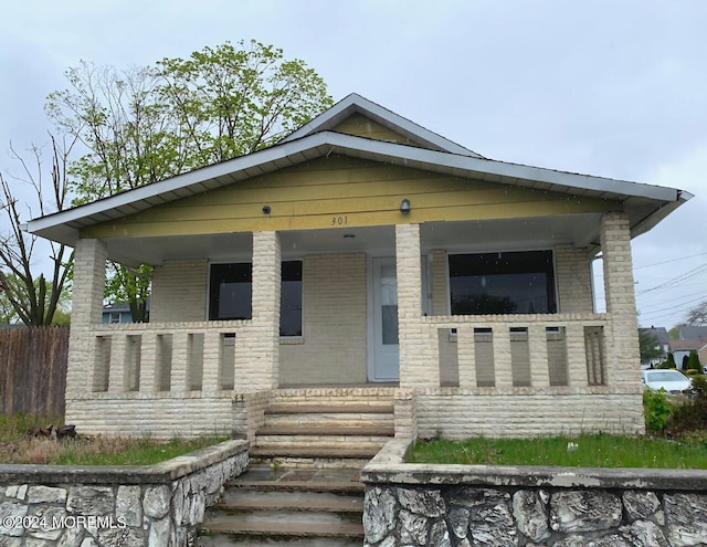 bungalow featuring brick siding and covered porch