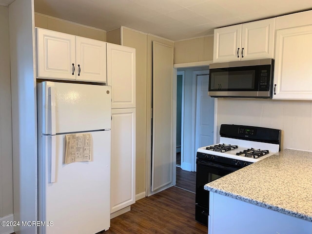 kitchen with dark wood-style flooring, freestanding refrigerator, white cabinets, gas range oven, and stainless steel microwave