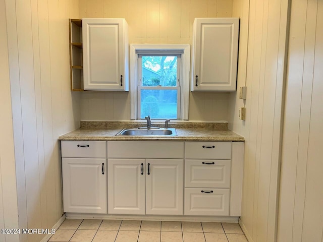 kitchen with wooden walls, open shelves, white cabinetry, and a sink