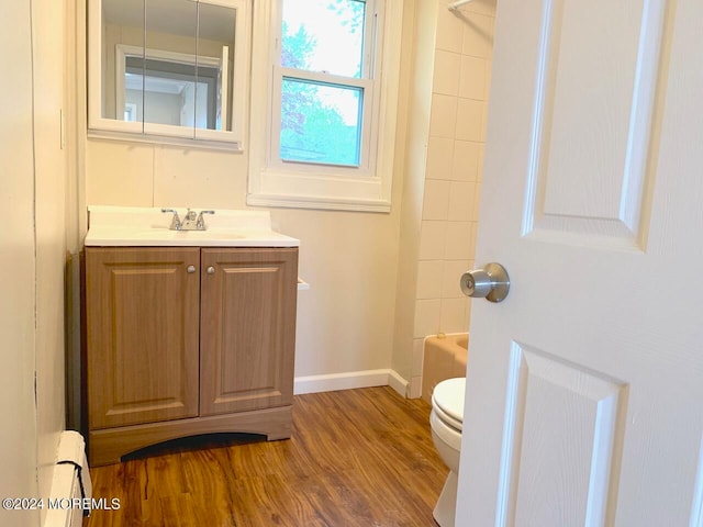 full bathroom with hardwood / wood-style floors, bathtub / shower combination, toilet, a baseboard radiator, and vanity