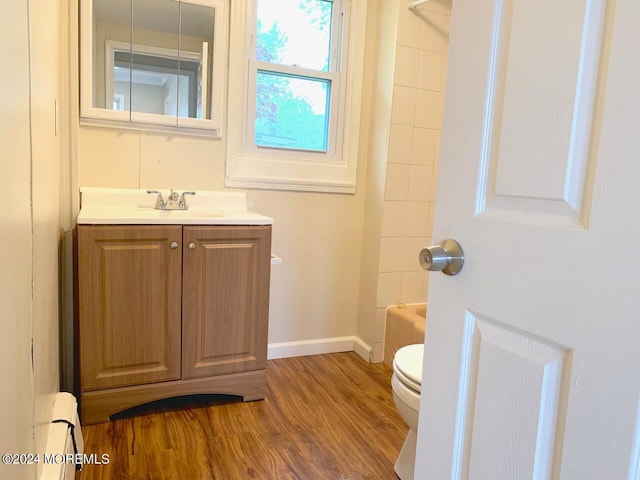 bathroom with baseboards, toilet, wood finished floors, vanity, and  shower combination