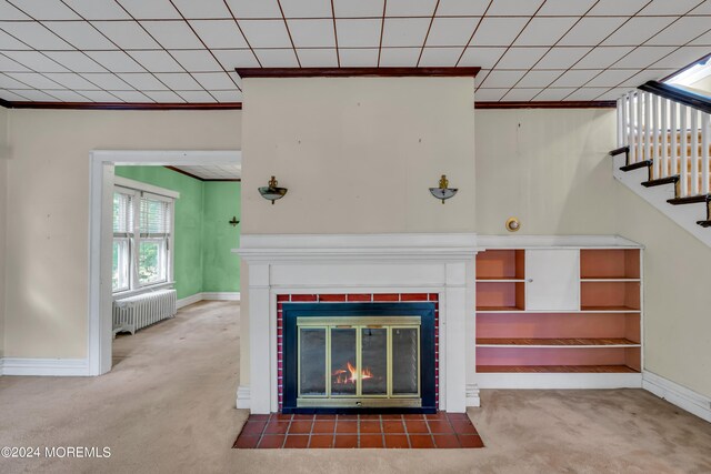 unfurnished living room featuring carpet floors, ornamental molding, radiator, and a tiled fireplace