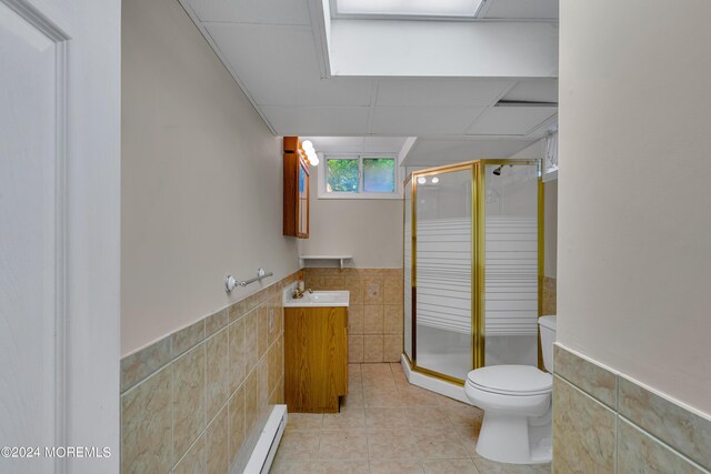 bathroom with tile walls, walk in shower, tile patterned floors, vanity, and toilet