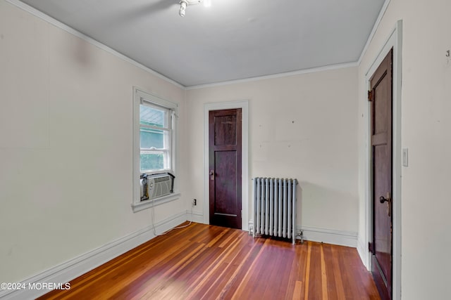 unfurnished room with cooling unit, ornamental molding, hardwood / wood-style floors, and radiator heating unit