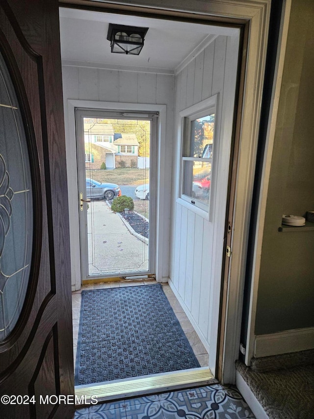 entryway with crown molding and wood walls