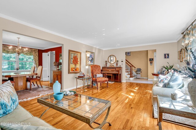 living room with ornamental molding, light wood-type flooring, and a notable chandelier