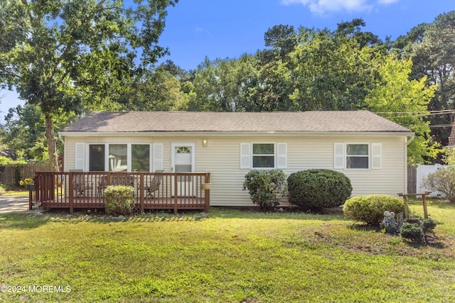 ranch-style home featuring a front lawn and a wooden deck