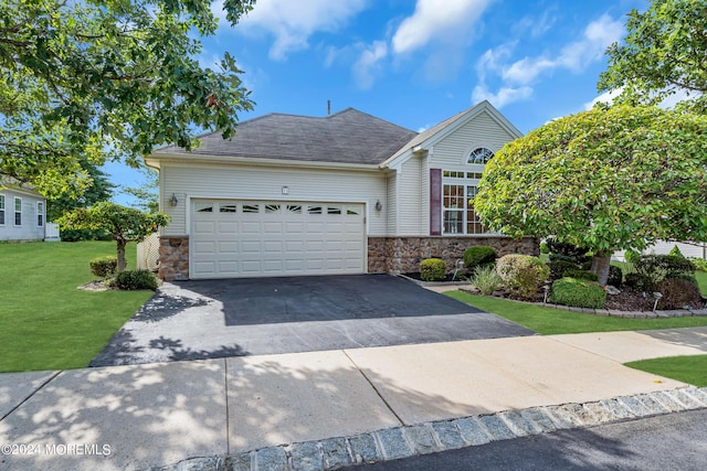 view of front of property featuring a shingled roof, an attached garage, stone siding, driveway, and a front lawn