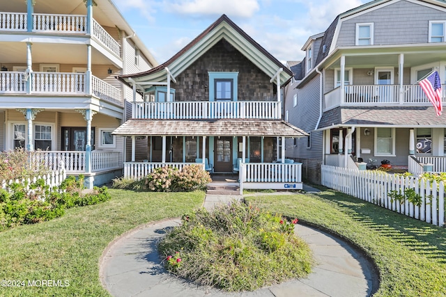 view of front facade with a balcony, covered porch, and a front lawn