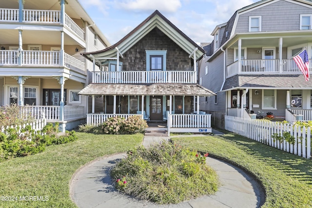 view of front of property featuring covered porch, fence, and a front yard