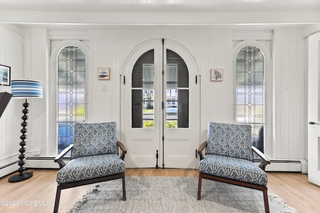 living area featuring arched walkways, baseboard heating, and wood finished floors