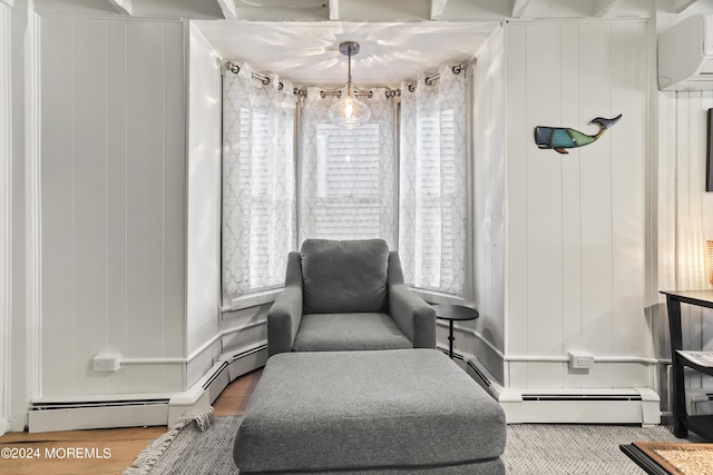 sitting room featuring baseboard heating, wood finished floors, and a wall mounted AC