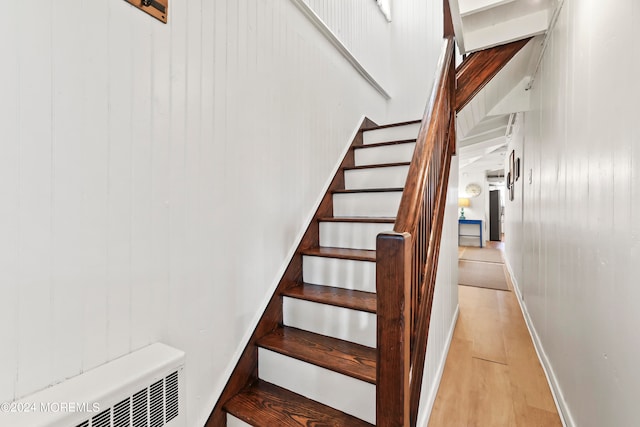 staircase with radiator heating unit and hardwood / wood-style flooring