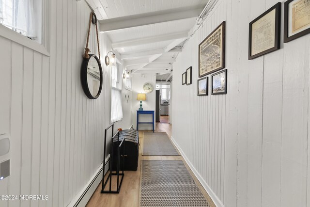 corridor featuring light wood-type flooring, wood walls, and beam ceiling