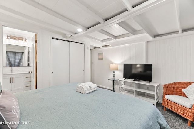 carpeted bedroom with connected bathroom, a closet, wooden walls, and beam ceiling