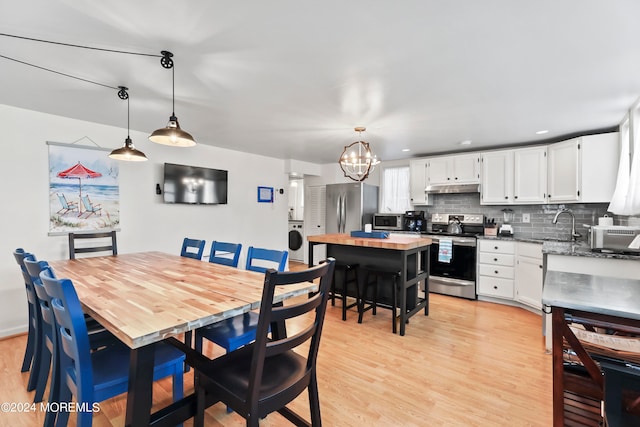 dining room featuring washer / clothes dryer, a notable chandelier, and light hardwood / wood-style floors