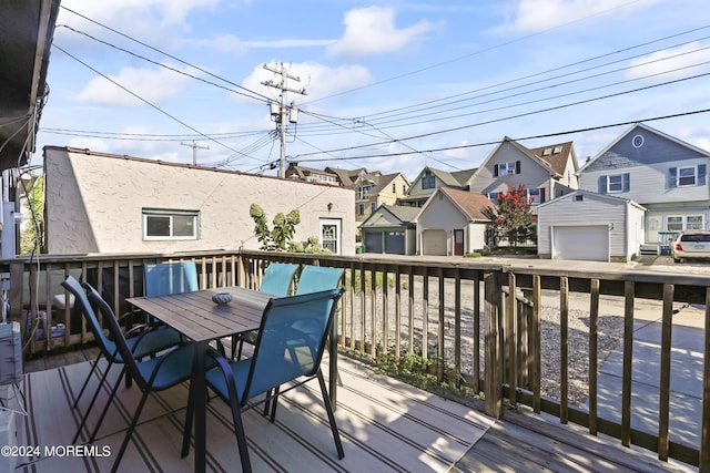 wooden terrace featuring a garage, outdoor dining area, and a residential view