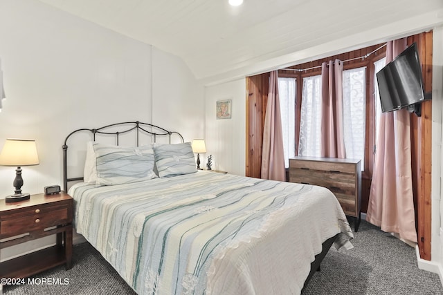 bedroom with dark colored carpet and lofted ceiling